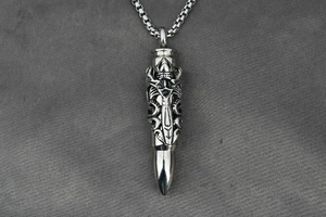 Macro detail of gothic style bullet pendant with intricate cross engravings on silver box chain
