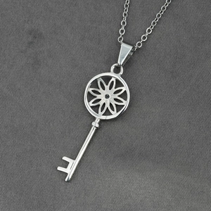 Collier avec pendentif clé en acier titane poli et découpe florale sur tissu gris