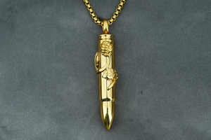 Macro detail of golden bullet pendant with embossed rose texture and box chain