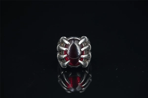 Macro detail of gothic dragon claw ring with large oval red gemstone on black mirror