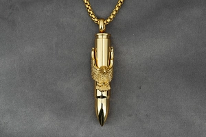 Close-up of golden bullet pendant with eagle relief and square box chain on velvet