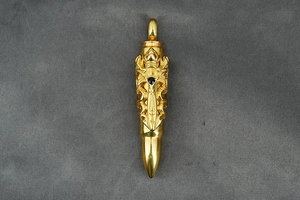 Detailed view of bullet pendant with hollow carvings and black stone inlay on gray fabric