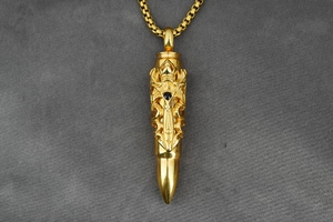 Detailed close-up of golden bullet pendant with gothic relief pattern and black gem