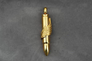 Detailed close-up of a golden bullet pendant with intricate embossed wing decorations