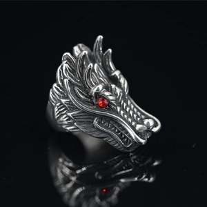Punk silver dragon head ring with detailed scales and red gemstone eyes on black background