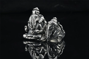 Detailed view of two vintage Ganesha stainless steel rings on a black reflective surface