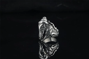 Detailed view of vintage Ganesh stainless steel ring with intricate carvings on black surface