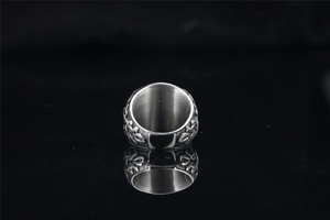 Macro shot of punk style silver wide band ring featuring abstract engraved patterns