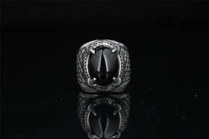 Macro detail of gothic titanium steel ring featuring black agate and dragon claw setting
