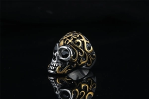 Macro detail of punk skull ring with black zircon eyes and golden flame patterns
