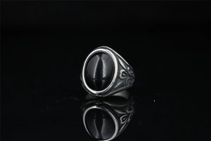 Detail of vintage Mayan style silver ring with large oval black gemstone and floral carvings