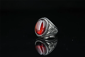Detail of vintage signet ring with red oval gemstone and ornate silver engraving