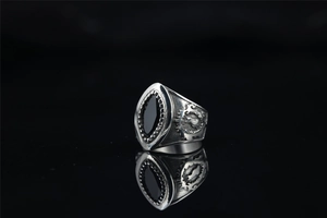 Macro detail of punk skull ring featuring a black marquise stone and relief wing pattern