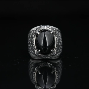 Vintage dragon claw ring for men featuring oval black agate stone on a reflective surface