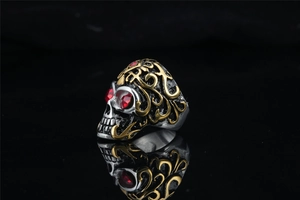 Macro shot of gothic skull ring with gold floral pattern and red rhinestone eyes