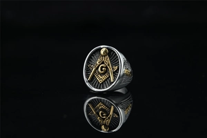 Detailed macro of vintage Masonic ring with golden G symbol on black face and steel band