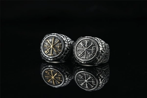 Macro shot of Viking compass rings with vintage finish on a reflective black surface