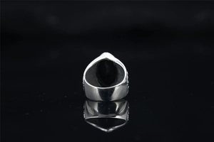 Detailed close-up of a vintage steel ring with black oval onyx and embossed side carvings