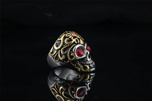 Detail of gothic skull ring in vintage silver with gold accents and red zircon eyes