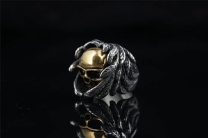 Macro detail of gothic skull ring with golden face and silver feather wings design