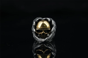 Macro shot of punk skull ring with golden skull and silver wings on dark background