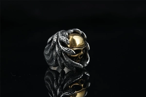 Macro detail of gothic skull ring with golden head and oxidized silver feather wings