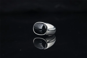 Gros plan d'une pierre noire ovale sur une bague en acier titane poli pour homme