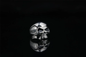 Gros plan détaillé d'une bague tête de mort en argent poli avec des ombres gothiques