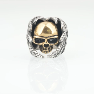 Punk rocker skull ring in gold and silver finish featuring wings design on white background