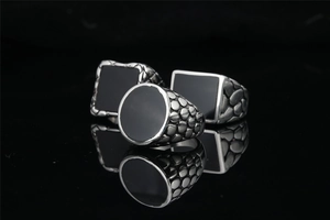 Macro detail of men's retro rings showing geometric black obsidian inlays and scale textures