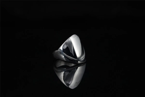 Macro shot of polished silver shield ring with mirror finish on black reflective base