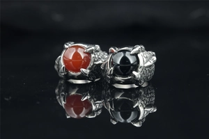 Detailed view of dragon claw rings featuring red and black gemstones on a reflective surface