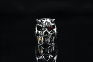 Macro shot of gothic skull ring with red gemstone eye and golden cigar detail