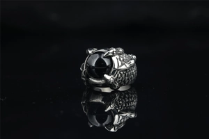 Macro shot of retro dragon claw ring featuring intricate scale details and a black stone