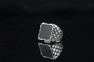Detail of vintage silver ring featuring side woven texture and square black stone