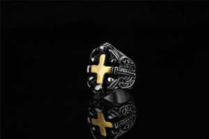 Detalle del anillo gótico hip hop con cruz dorada y relieves de calaveras en metal