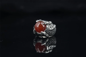 Detailed macro shot of vintage dragon claw ring with red gemstone and steel scales