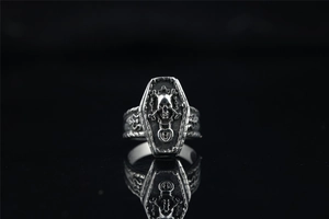 Détail de la bague cercueil gothique vintage avec relief de crâne et os croisés