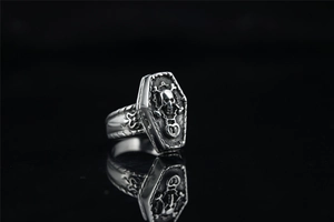 Gros plan sur une bague punk vintage présentant un crâne détaillé en forme de cercueil