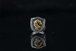 Close-up of shield ring with gold horse emblem on black textured background