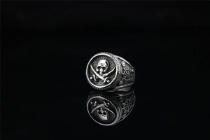 Detailed relief of pirate skull and crossed cutlasses on a vintage steel punk ring