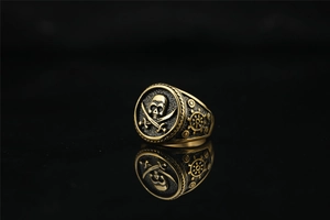 Detailed view of vintage pirate skull and crossed swords relief on gold steel ring