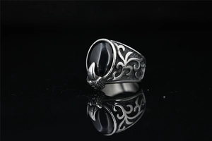 Macro shot of vintage steel ring with black gemstone and intricate eagle claw engraving