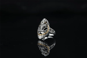 Gros plan d'une bague couronne rétro avec accents dorés et cristal sur fond noir poli