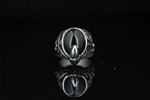 Macro shot of gothic dragon claw ring holding a black stone on a reflective surface
