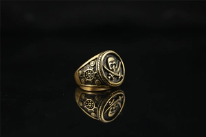 Macro view of vintage gold pirate skull ring with cross cutlass and ship wheel details