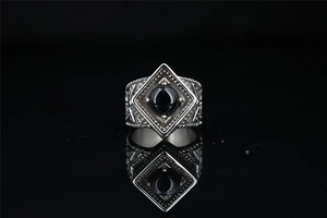 Macro shot of vintage silver-tone ring with black gemstone on mirror surface