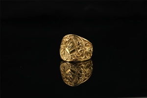 Macro shot of gold Masonic ring with detailed engraved side scrolls on black background