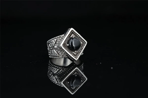 Macro detail of vintage square titanium ring with black gemstone and engraved relief