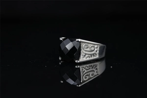 Macro detail of vintage men's steel ring with faceted black gemstone and carved patterns